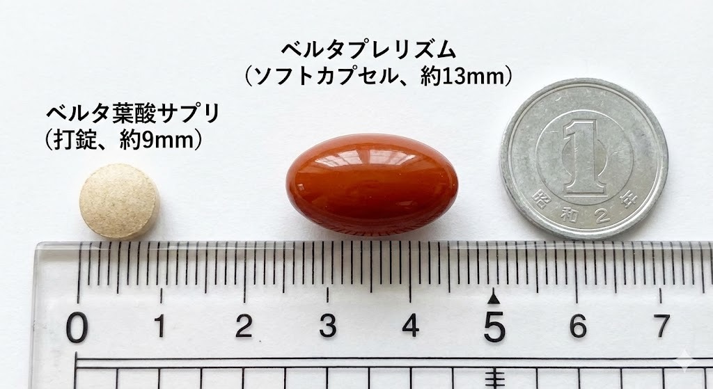 ベルタ葉酸サプリ（打錠、約9mm）とベルタプレリズム（ソフトカプセル、約13mm）の実物を並べた比較写真。定規と1円玉を横に置いてサイズ感と形状の違いを分かりやすく示している。